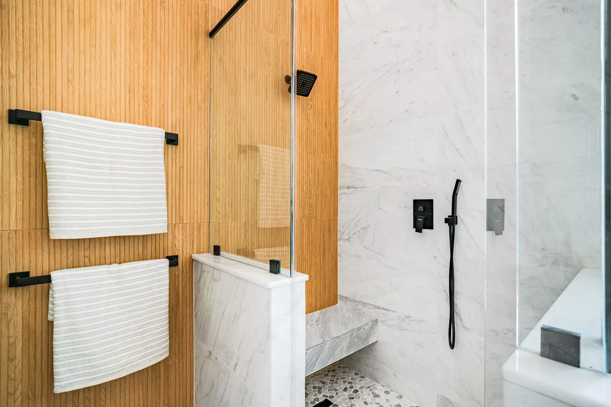 ADA roll-in shower in a Florida bathroom with a folding seat, hand-shower, and grab bars mounted at code height