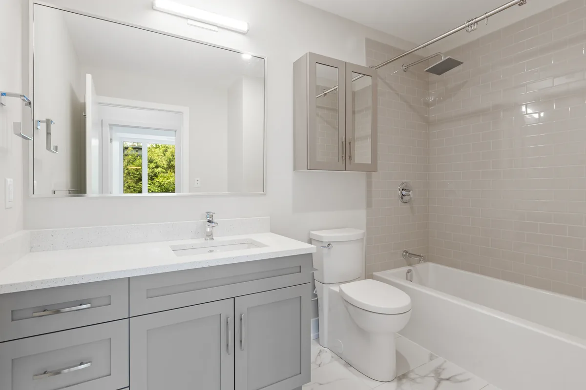 A finished Florida full bathroom remodel with a curbless walk-in shower, dual vanity, and humidistat exhaust fan