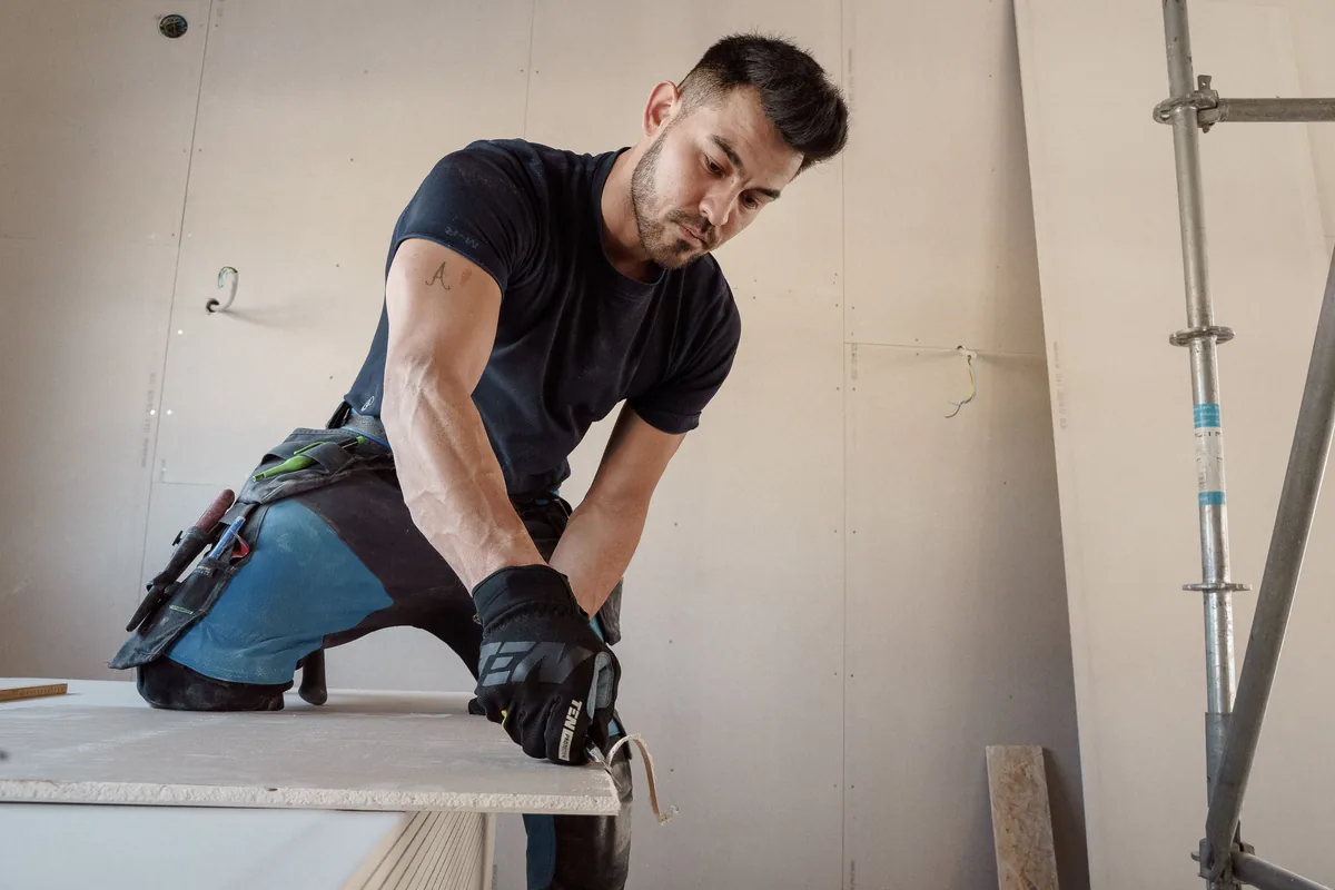 Installer scribing and fitting baseboard over a new floor's expansion gap in a Florida home