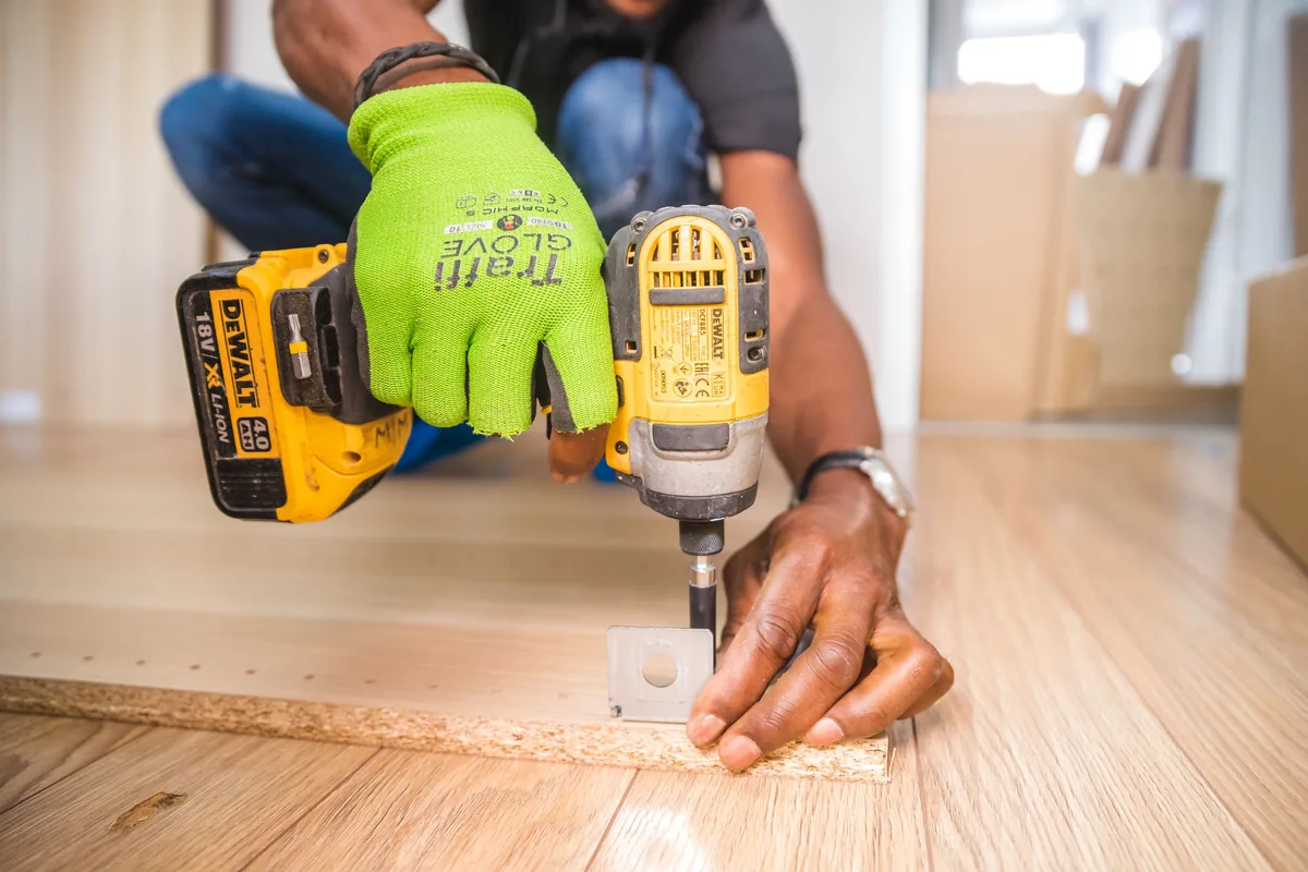 Installer power-stretching carpet over a moisture-resistant pad and tackless strips in a Florida bedroom