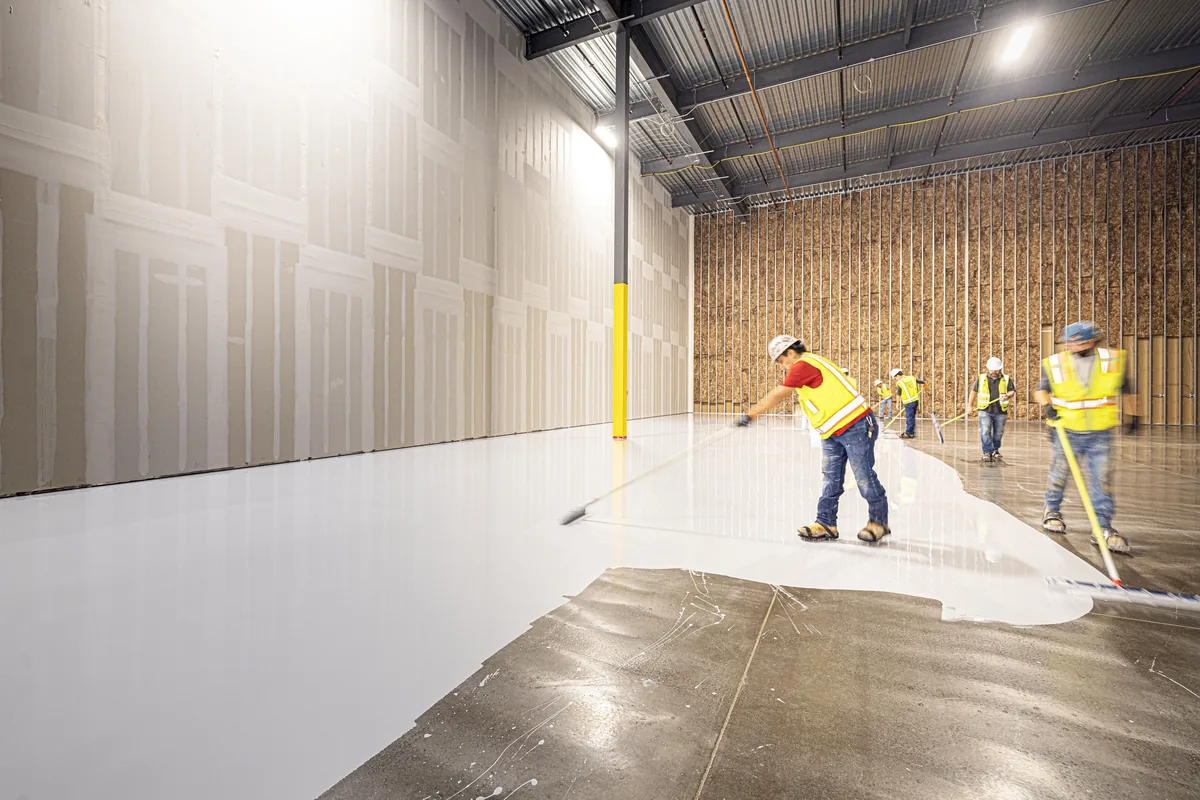 Installer applying a chemical densifier to a Florida concrete slab during the polishing process