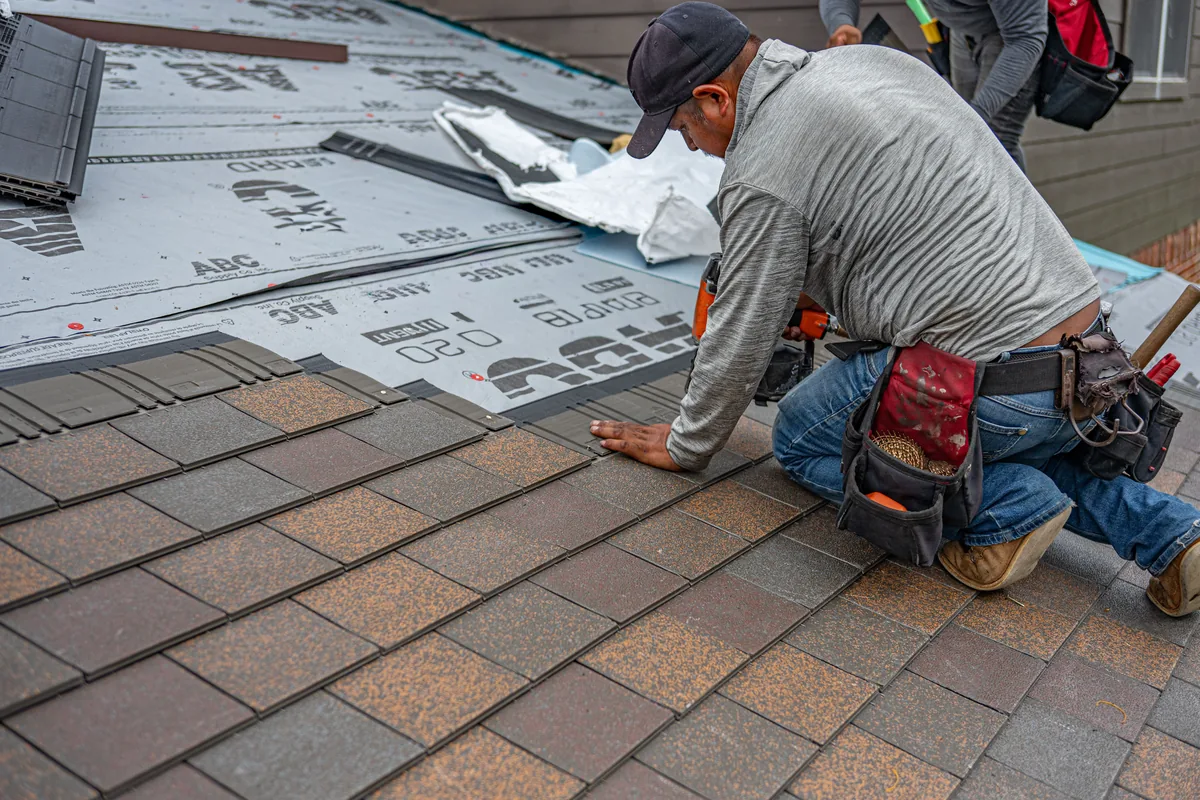 Installer setting an expansion-gap spacer along a wall while floating laminate flooring in a Florida room