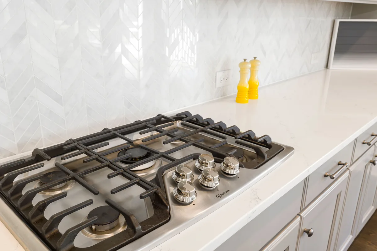 Kitchen backsplash tile set behind a range with sealed grout joints and a caulked tile-to-counter line