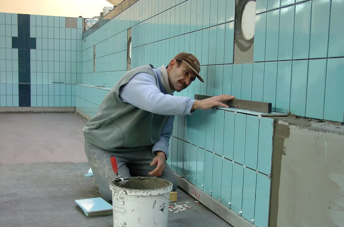 Installer applying epoxy grout to a Florida kitchen backsplash and tooling the joints