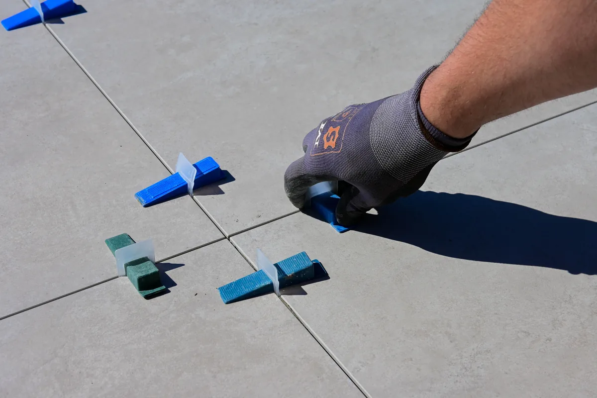 Installer aligning mesh-backed mosaic sheets flat and tooling epoxy grout into the joints in a Florida bathroom